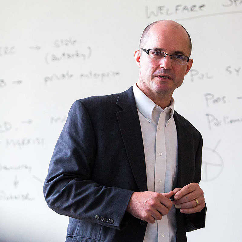 a professor standing in front of a whiteboard and instructing a class